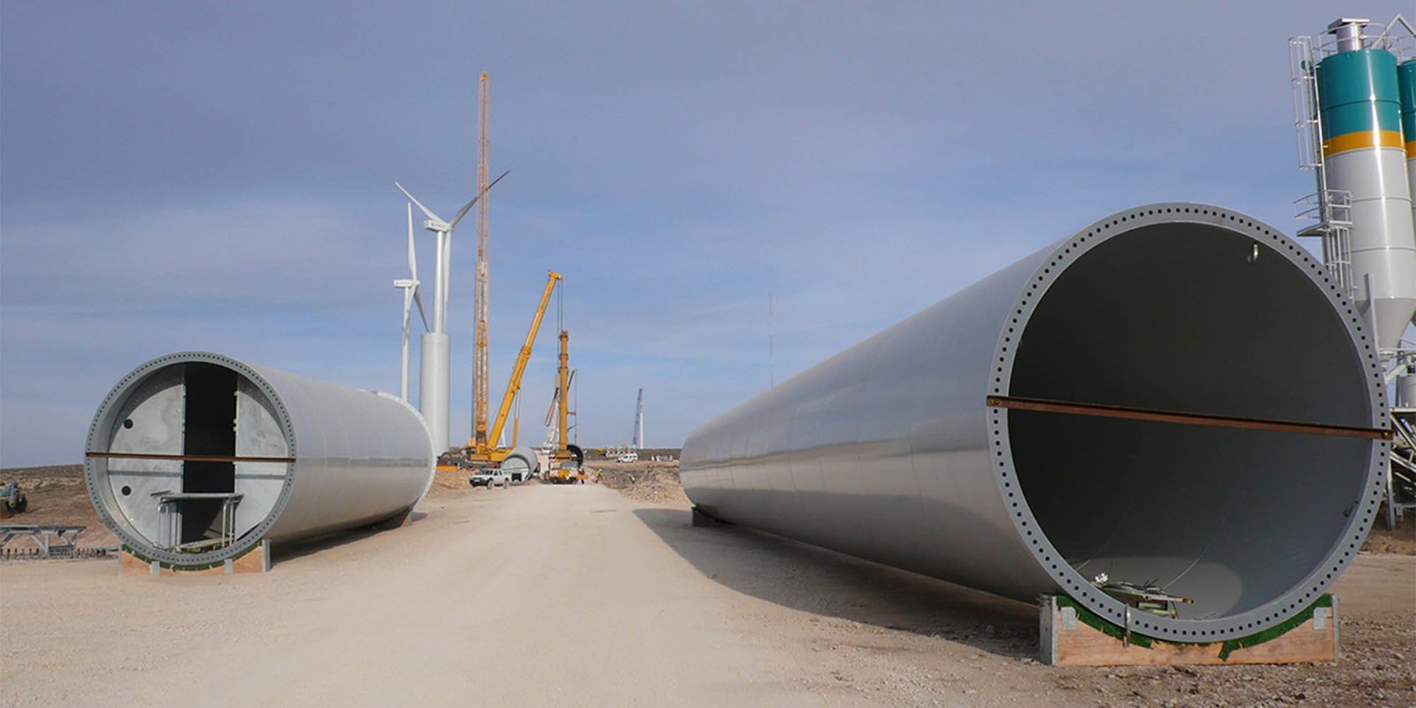 Montaje de estructuras eólicas con tramos de torre y grúas en obra